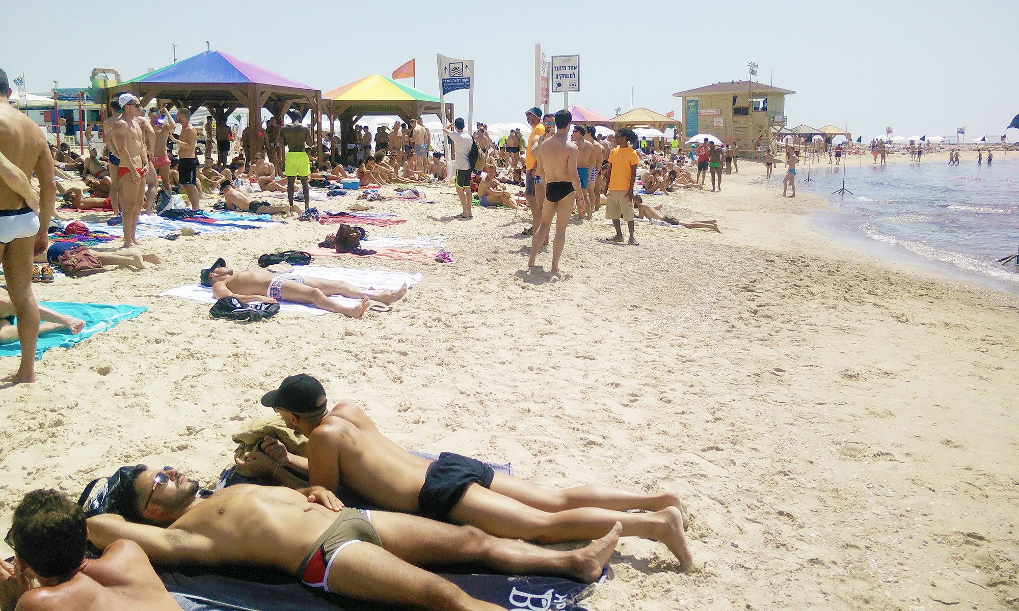 many men sunbathe or stroll around the gay beach called Hilton Beach in Tel Aviv